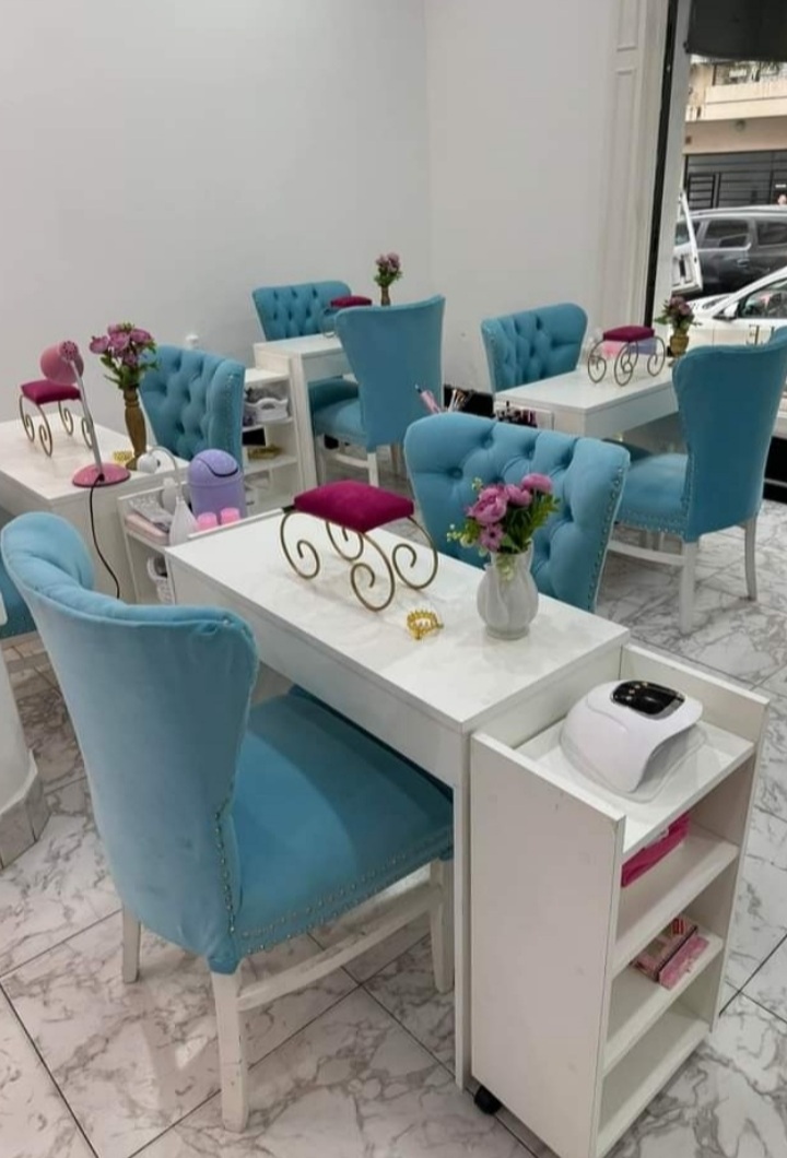 Interior del salón LE BELLE, sillones de manicura color turquesa, mesas blancas con detalles dorados y flores